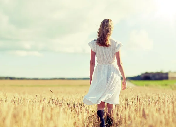 Молодая женщина в белом платье ходит по полю — стоковое фото