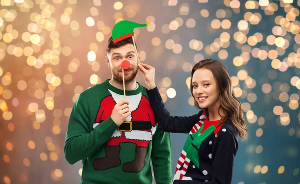 Casal com adereços de festa de Natal em camisolas feias — Fotografia de Stock