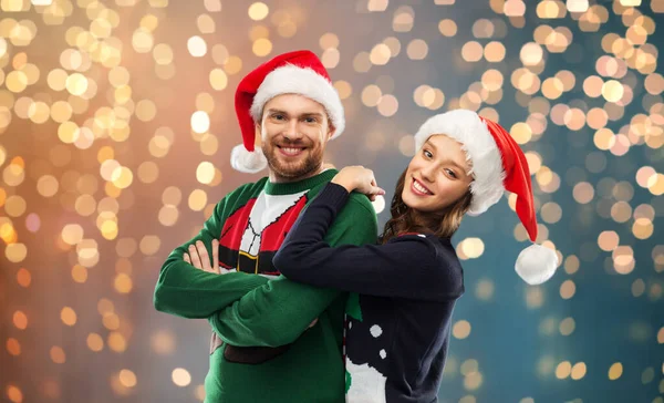 Feliz pareja en suéteres de Navidad y sombreros de santa —  Fotos de Stock