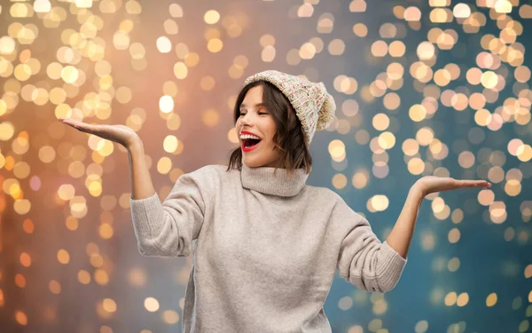 Ung kvinna i vinter hatt håller något — Stockfoto