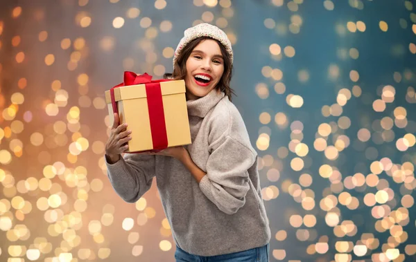 Young woman in knitted winter hat holding gift box — Stock Photo, Image