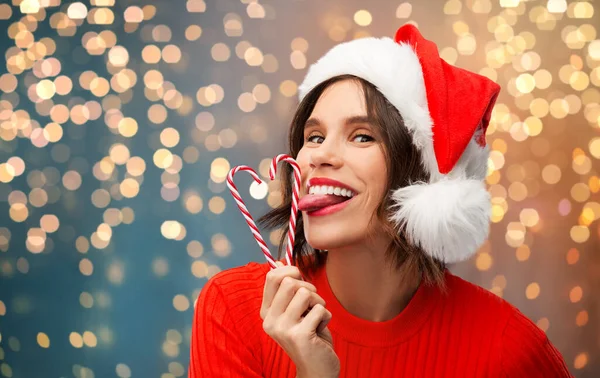 Vrouw in santa hoed likt snoep stokken op kerst — Stockfoto