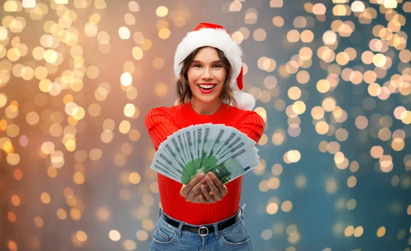 Happy woman in santa hat with money on christmas — Stock Photo, Image
