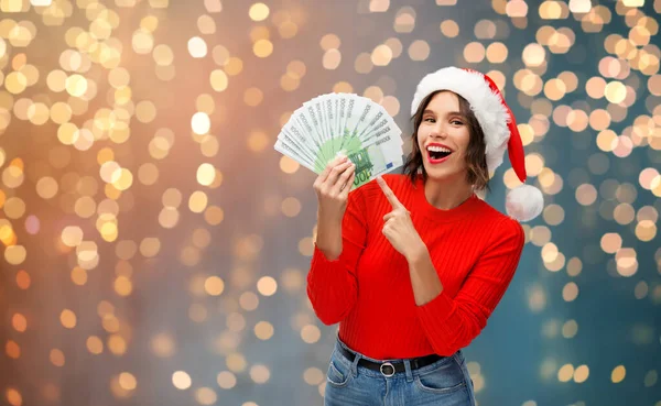 Happy woman in santa hat with money on christmas — Stock Photo, Image