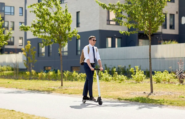 Businessman with backpack riding electric scooter — Stock Photo, Image