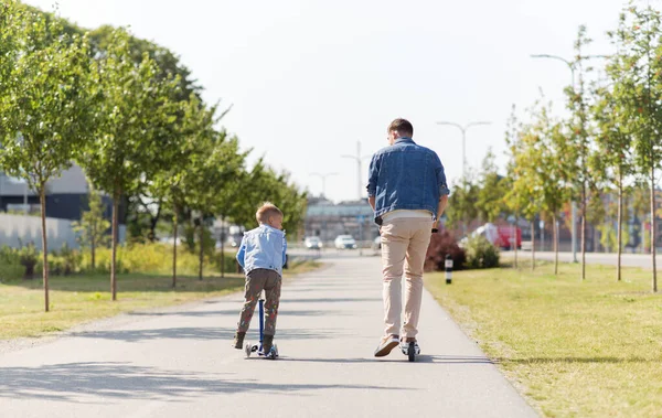 Gelukkig vader en zoontje paardrijden scooter in stad — Stockfoto