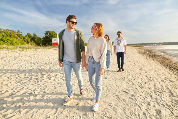 Happy friends walking along summer beach — Stock Photo, Image