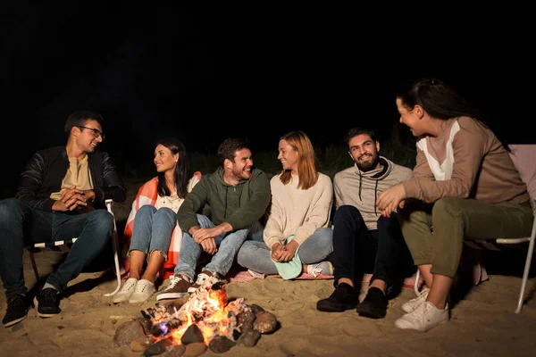Groupe d'amis assis au feu de camp sur la plage — Photo