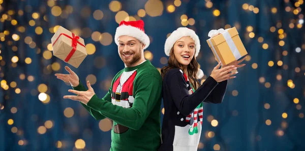 Feliz pareja en suéteres de Navidad con regalos —  Fotos de Stock