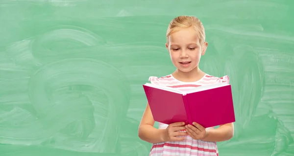 Lächelndes kleines Mädchen liest Buch in der Schule — Stockfoto