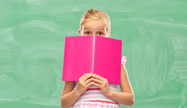 Menina se escondendo sobre livro na escola — Fotografia de Stock