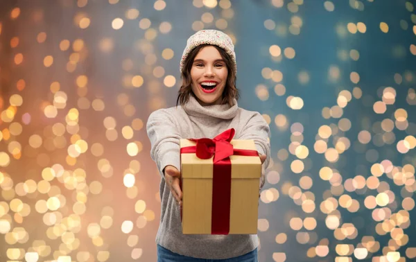 Jonge vrouw in gebreide winter hoed houden geschenkdoos — Stockfoto