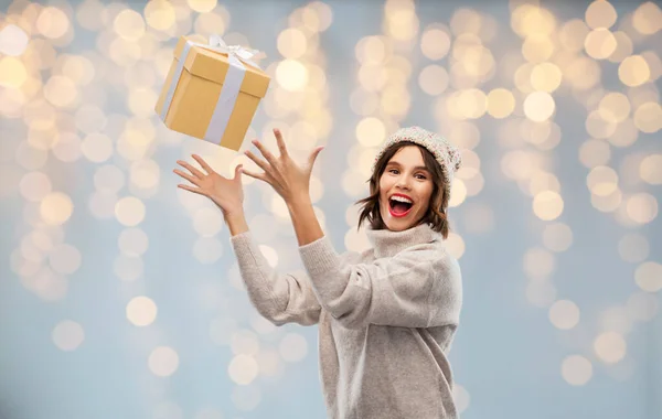 Young woman in winter hat catching gift box — Stock Photo, Image