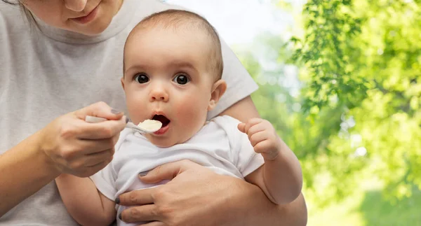 Primer plano de la madre con cuchara alimentando al pequeño bebé — Foto de Stock