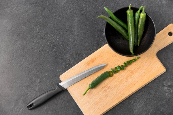 Pimentas verdes e faca na tábua de corte — Fotografia de Stock