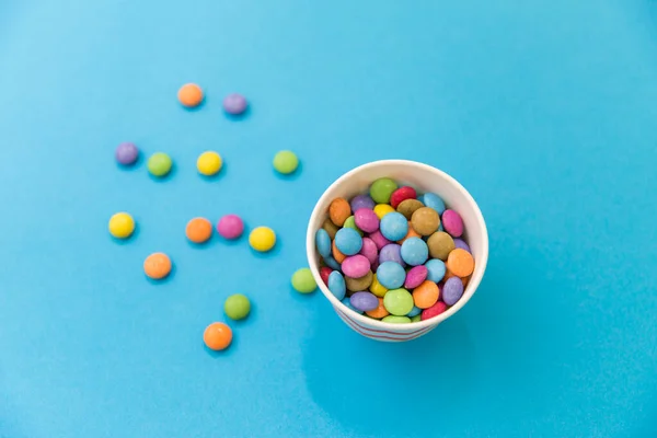 Gotas de doces em copo de papel no fundo azul — Fotografia de Stock