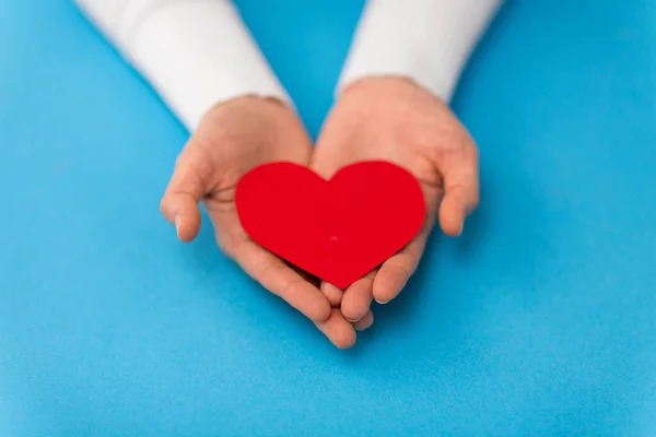 Mains tenant rouge forme de coeur sur fond bleu — Photo