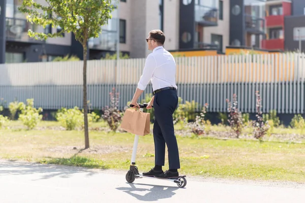 Geschäftsmann mit Papiertüte zum Mitnehmen fährt Roller — Stockfoto