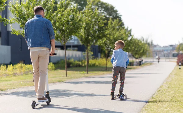 Feliz padre e hijo pequeño montar scooter en la ciudad —  Fotos de Stock