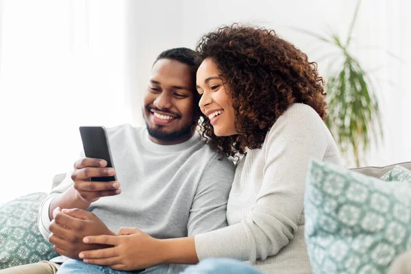 Pareja afroamericana con smartphone en casa — Foto de Stock