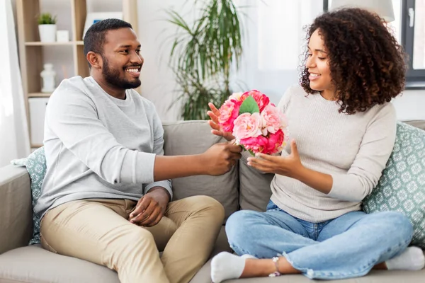 Feliz pareja con ramo de flores en casa — Foto de Stock