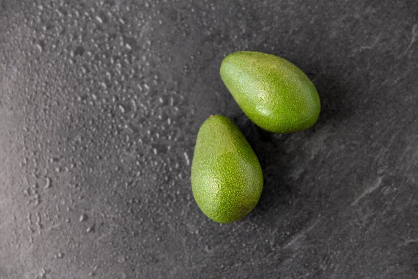 Islak taş zemin üzerinde iki avokado — Stok fotoğraf