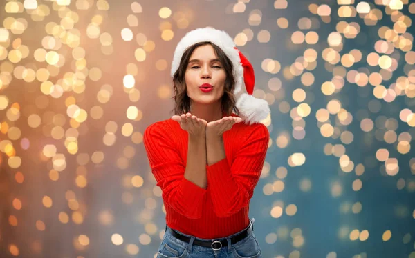 Happy young woman in santa hat sending air kiss — Stock Photo, Image