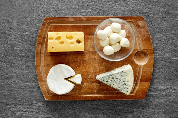 Different kinds of cheese on wooden cutting board — Stock Photo, Image