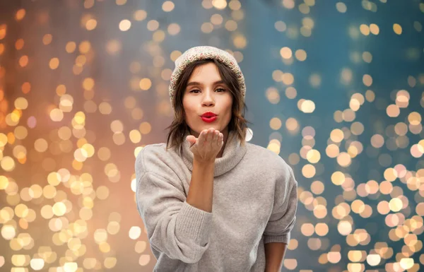 Jonge vrouw in gebreide winter hoed verzenden lucht kus — Stockfoto