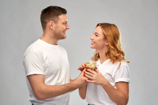 Glückliches Paar in weißen T-Shirts mit Weihnachtsgeschenk — Stockfoto