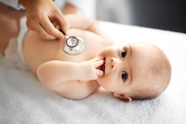 Médico con estetoscopio escuchando al bebé paciente —  Fotos de Stock