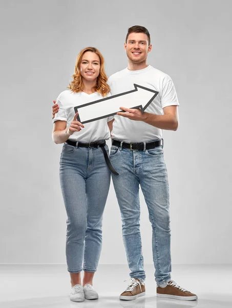 Feliz pareja en camisetas blancas con flecha a la derecha — Foto de Stock