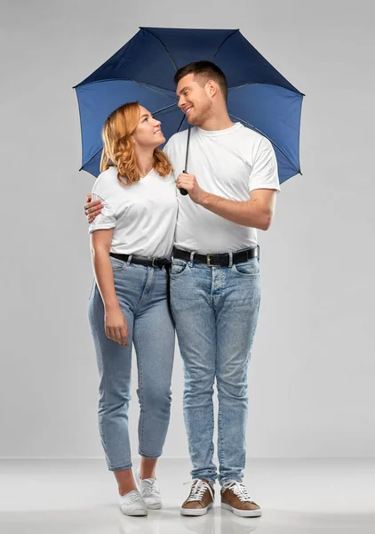 Glückliches Paar in weißen T-Shirts mit Regenschirm — Stockfoto