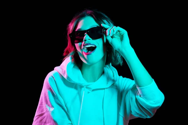 Vrouw dragen hoodie in neon lichten over zwart — Stockfoto