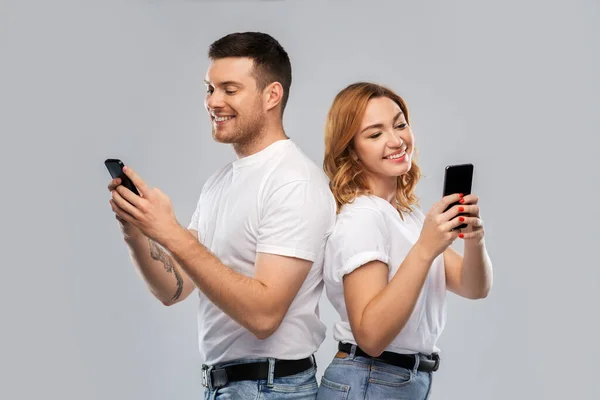 Glückliches Paar in weißen T-Shirts mit Smartphones — Stockfoto