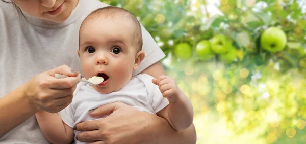 Close up de mãe com colher alimentando pequeno bebê — Fotografia de Stock