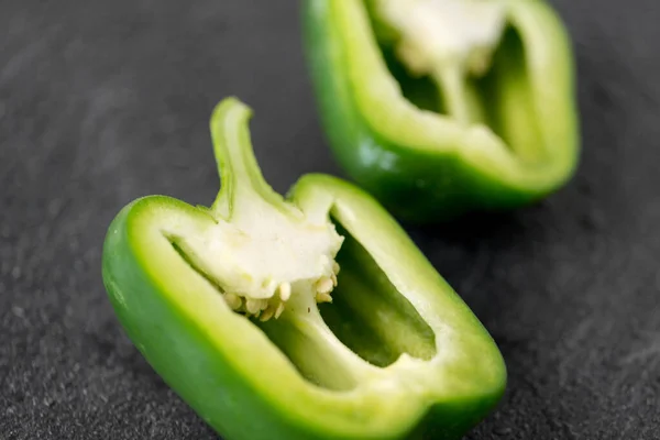 Cut green pepper on slate stone background — Stock Photo, Image