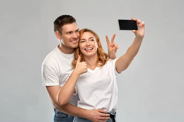 Feliz pareja en blanco camisetas tomando selfie — Foto de Stock