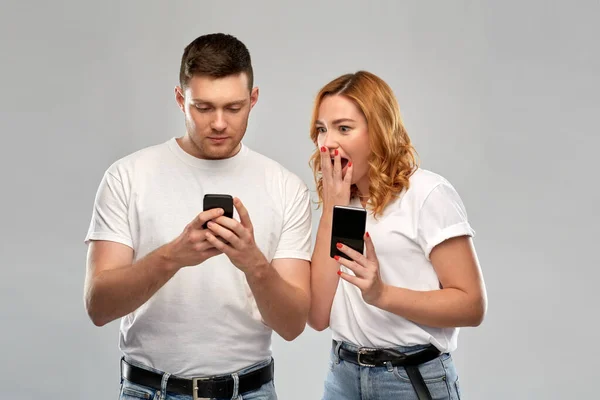 Casal feliz em camisetas brancas com smartphones — Fotografia de Stock