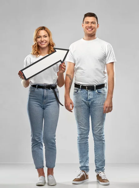 Feliz pareja en camisetas blancas con flecha a la derecha — Foto de Stock