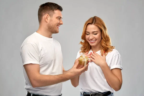 Szczęśliwa para w białych koszulkach z prezentem świątecznym — Zdjęcie stockowe