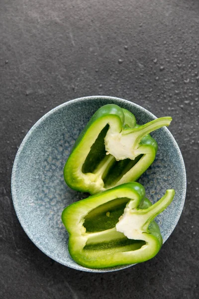 Cut green pepper in bowl on slate stone background — Stock Photo, Image