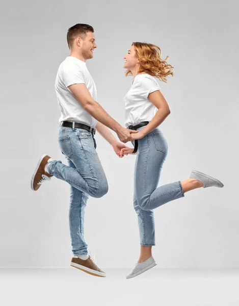 Щаслива пара в білих футболках стрибає — стокове фото