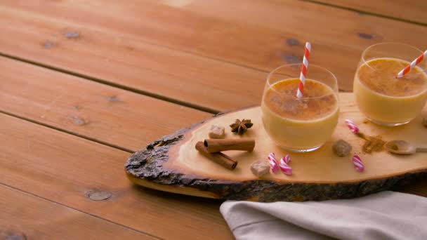 Glasses of eggnog, ingredients and spices on wood — Stock Video