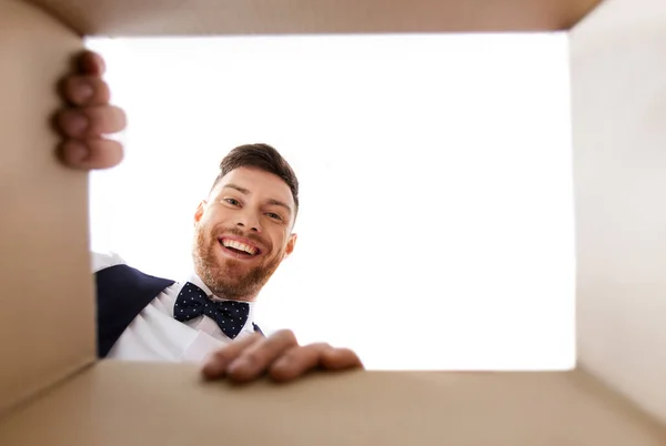 Щасливий молодий чоловік дивиться у відкриту подарункову коробку — стокове фото