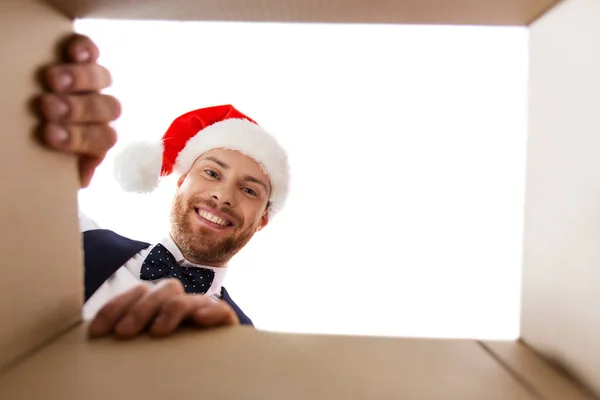 Glücklicher junger Mann blickt in offenes Weihnachtsgeschenk — Stockfoto