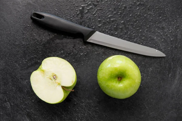 Maçãs verdes e faca de cozinha no fundo de ardósia — Fotografia de Stock