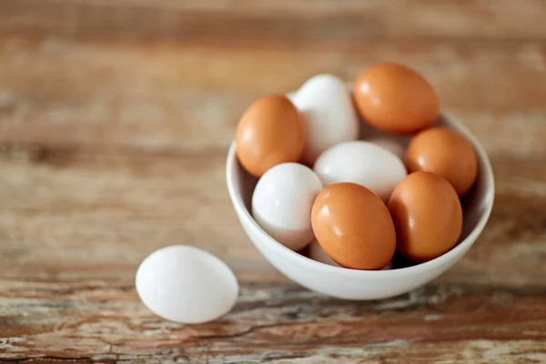 Κλείσιμο των αυγών σε κεραμικό μπολ σε ξύλινο τραπέζι — Φωτογραφία Αρχείου