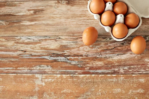 Закрытие яиц в картонной коробке на деревянном столе — стоковое фото
