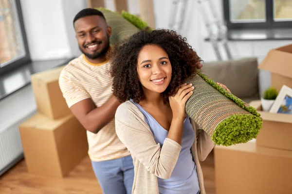 Glückliches Paar mit Teppich zieht in neues Zuhause — Stockfoto